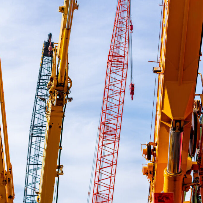 Selective focus on crawler crane against blue sky. Real estate industry. Red crawler crane use reel lift up equipment in construction site. Crane for rent. Crane dealership for construction business.