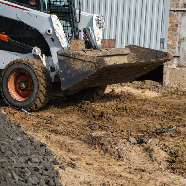 White skid steer loader at a construction site working with a soil. Industrial machinery. Industry